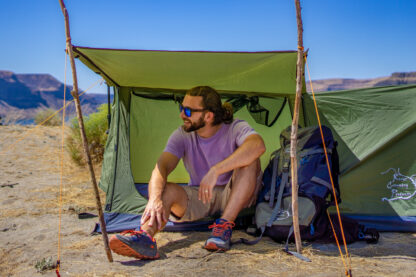 River Country Products Trekker 1A trekking pole tent backpacking tent set up next to river with man posing