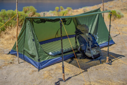 River Country Products Trekker 1A trekking pole tent backpacking tent set up next to river with backpack